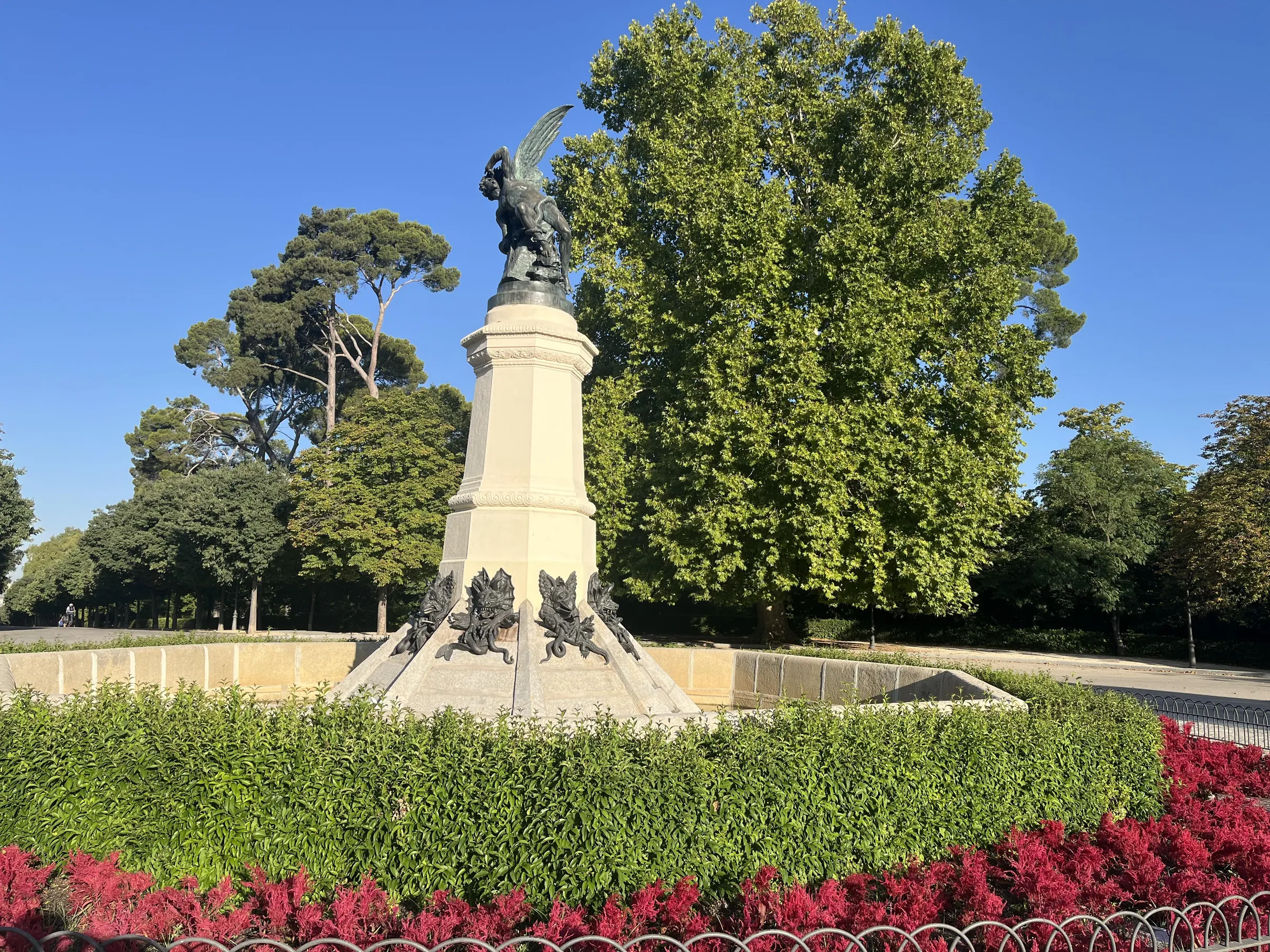Arce plateado junto al monumento, con el follaje abierto contra el cielo azul